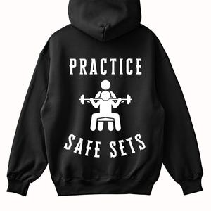 Könnte beinhalten: Schwarzer Kapuzenpullover mit weißem Text und Grafik. Der Text lautet "PRACTICE SAFE SETS" mit einer Gewichtheber-Illustration. Der Kapuzenpullover hat eine Kapuze mit Kordelzug und lange Ärmel.