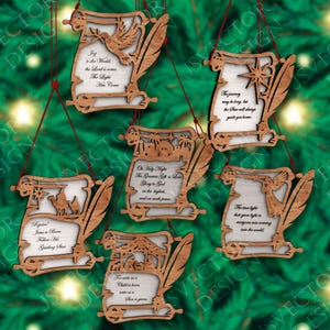 Puede incluir: Adornos navideños de madera con forma de pergaminos, cada uno con un diseño y mensaje únicos. Los adornos presentan detalles cortados con láser, incluyendo palomas, estrellas y escenas bíblicas. El texto en los pergaminos incluye frases como "Joy to the World" y "Oh Holy Night."