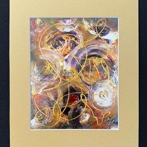 Puede incluir: Impresión artística abstracta con círculos arremolinados en tonos marrón, morado y dorado. La obra de arte tiene líneas doradas y está enmarcada en un passe-partout de color beige claro, sobre un fondo negro.