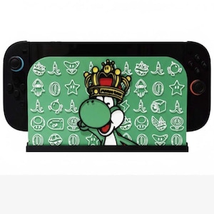 May include: Black Nintendo Switch Joy-Con controllers with a green stand featuring Yoshi wearing a crown. The stand has a pattern of white icons and the words "Mario Kart".