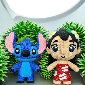 May include: Two knitted figurines of characters from the animated film Lilo & Stitch. One is blue with large ears, the other is a girl in a red dress. They are set against a backdrop of green plants.