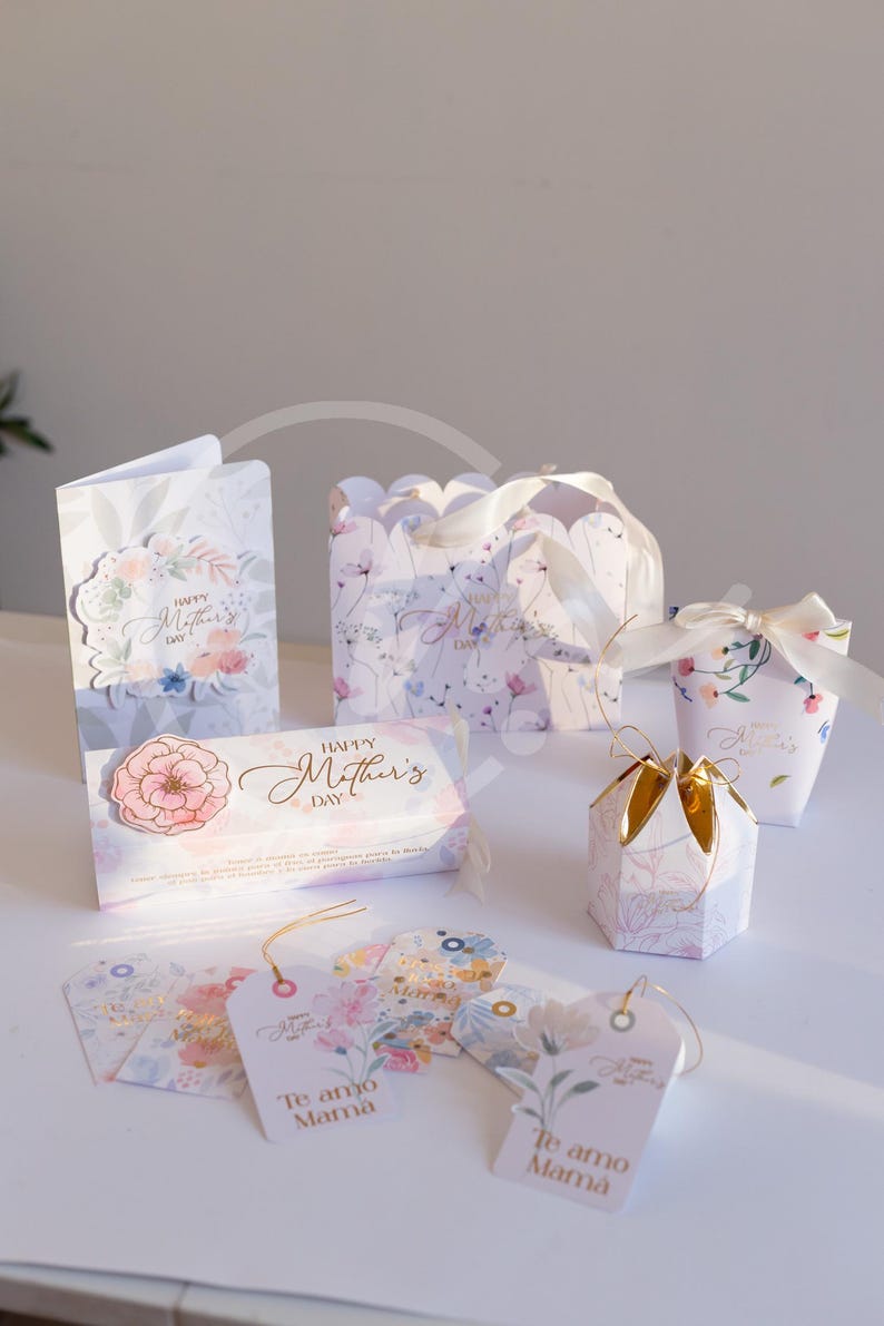 K&ouml;nnte beinhalten: Eine Auswahl an Muttertagsgeschenken, darunter Karten, Geschenkboxen und Anh&auml;nger. Die Artikel weisen florale Designs und die S&auml;tze "Happy Mother's Day" und "Te amo Mama" auf. Die Farbpalette umfasst Pastellt&ouml;ne und goldene Akzente.