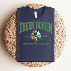 May include: Navy blue t-shirt featuring the text "GREEN GOBLIN" in green, with a cartoon illustration of the Green Goblin character. The shirt also includes the text "EST 2021" and "SPIDEY AND HIS AMAZING FRIENDS".