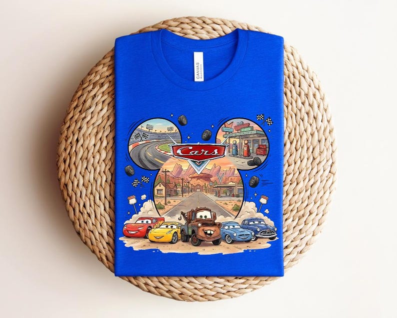 Puede incluir: Una camiseta azul real con un estampado gr&aacute;fico del logotipo de Disney Pixar Cars y personajes como Rayo McQueen, Mate y otros. El dise&ntilde;o est&aacute; dispuesto en forma de orejas de Mickey Mouse con escenas de una pista de carreras y Radiator Springs.