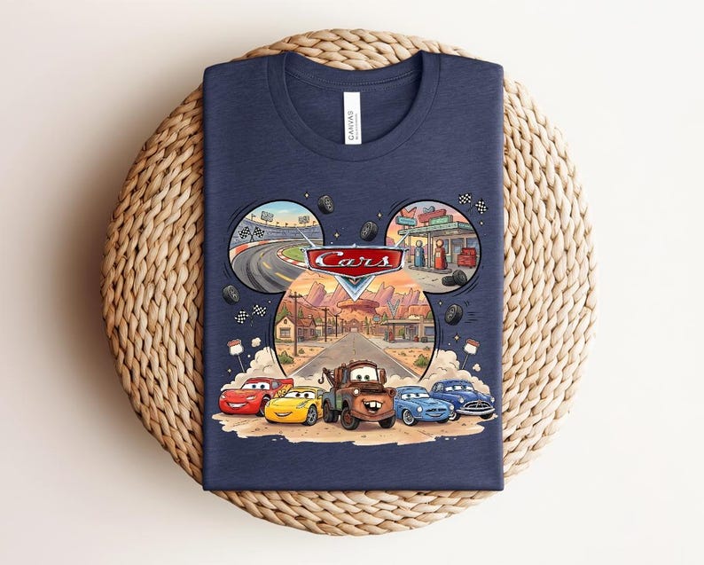 Puede incluir: Una camiseta azul marino con un estampado gr&aacute;fico de los personajes de Disney Pixar Cars, incluyendo a Rayo McQueen y Mate. El dise&ntilde;o incluye un marco con forma de orejas de Mickey que muestra escenas de una pista y Radiator Springs.