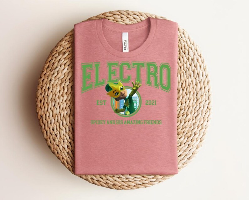 May include: A dusty rose t-shirt with the word "ELECTRO" in green block letters. Below the word is a cartoon image of a character in green and yellow. The text "EST 2021" and "SPIDEY AND HIS AMAZING FRIENDS" are also printed on the shirt.