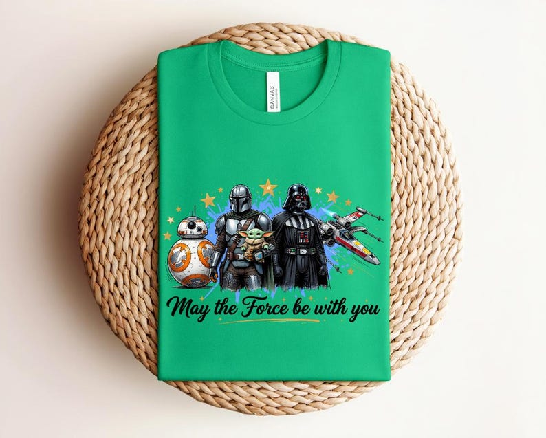 Pode incluir: Uma t-shirt verde brilhante com uma impress&atilde;o gr&aacute;fica de BB-8, O Mandaloriano, Grogu e Darth Vader ao lado de um ca&ccedil;a estelar X-wing. O design inclui estrelas amarelas, salpicos de tinta azul e o texto May the Force be with you.