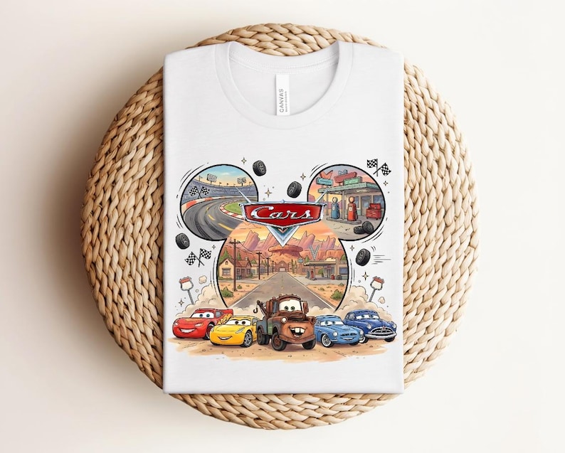 Puede incluir: Una camiseta blanca con un estampado gr&aacute;fico del logotipo de Disney Pixar Cars y personajes como Rayo McQueen, Cruz Ram&iacute;rez y Mate. El dise&ntilde;o incluye escenas circulares de una pista de carreras, una gasolinera y un paisaje de carretera des&eacute;rtica.