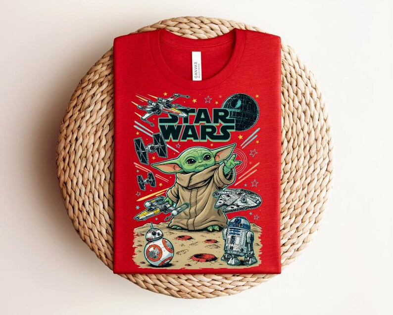 Puede incluir: Una camiseta roja de cuello redondo con un estampado gr&aacute;fico de Star Wars. El dise&ntilde;o incluye a Grogu, BB-8, R2-D2 y varias naves espaciales como el X-wing y el Halc&oacute;n Milenario sobre un fondo espacial con el logotipo de Star Wars en negro.