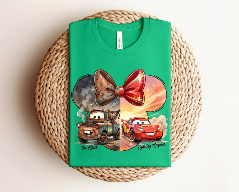 May include: A bright green t-shirt featuring a graphic of a bow shape containing two characters from the movie Cars. On the left, a brown rusty tow truck labelled Tow Mater. On the right, a red race car labelled Lightning McQueen.