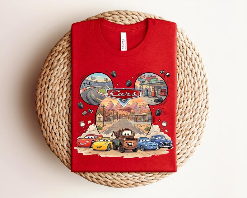 Puede incluir: Una camiseta roja con un estampado gr&aacute;fico del logotipo de Disney Pixar Cars y personajes como Rayo McQueen y Mate. El dise&ntilde;o est&aacute; dispuesto en forma de orejas de Mickey Mouse con escenas de un circuito de carreras y Radiator Springs.
