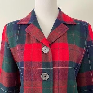 May include: A red, green, and navy plaid jacket with a classic collar and three large, round buttons. The jacket is displayed on a mannequin and features a traditional tartan pattern.