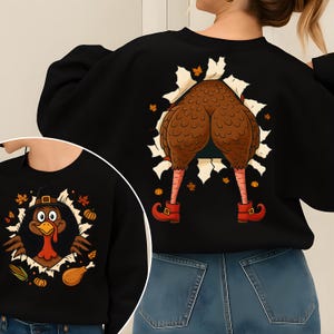 May include: Black sweatshirt with a Thanksgiving turkey design. The front features a cartoon turkey wearing a pilgrim hat. The back shows a turkey's rear end and legs. The design includes fall leaves and pumpkins.