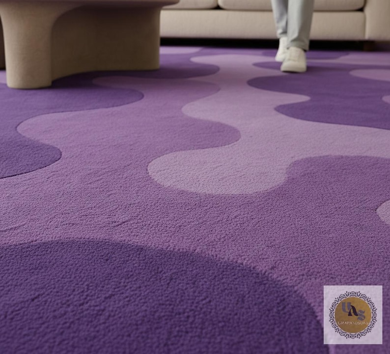 May include: A plush, purple area rug with a wavy, abstract design in varying shades of violet. The rug's texture is visible, and the design creates a flowing pattern across the floor. A person is walking on the rug.