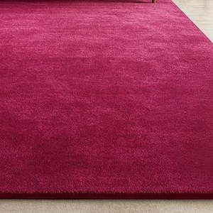 May include: A large, rectangular magenta rug with a soft, plush texture. The rug fills most of the frame, with a small portion of a light-colored floor visible in the background. The rug's color is a deep, vibrant shade of pink.