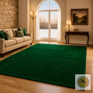 May include: A large, rectangular emerald green rug dominates the foreground of a living room scene. The rug sits on a light-colored hardwood floor, complementing the neutral tones of the sofa and brick wall. A window offers a view of a snowy landscape.