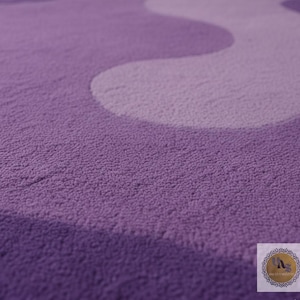 May include: A close-up of a plush, textured rug in shades of purple and lavender. The design features a wavy pattern, creating a soft and inviting aesthetic. The rug's surface appears dense and comfortable.