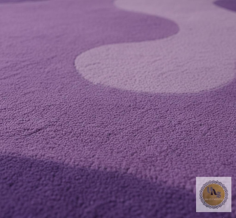 May include: A close-up of a plush, textured rug in shades of purple and lavender. The design features a wavy pattern, creating a soft and inviting aesthetic. The rug's surface appears dense and comfortable.