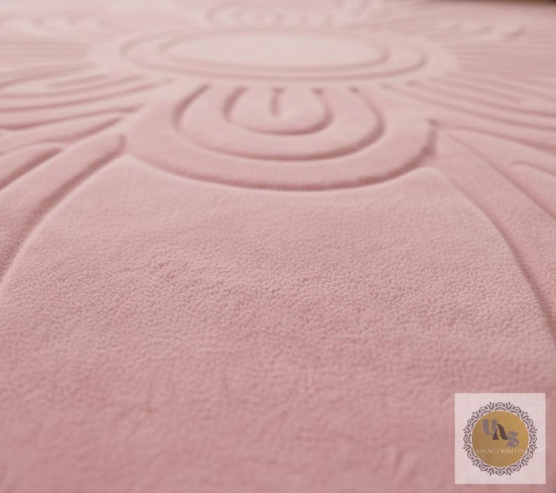 Puede incluir: Primer plano de una alfombra de color rosa empolvado con un dise&ntilde;o floral circular en relieve. La alfombra tiene una superficie suave y texturizada y un patr&oacute;n detallado. El dise&ntilde;o est&aacute; centrado e irradia hacia afuera.