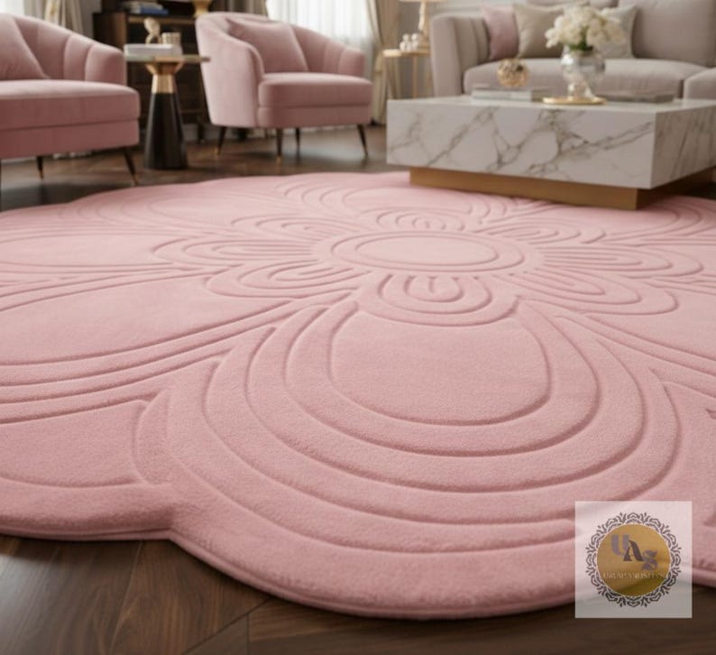Puede incluir: Una alfombra grande y redonda de color rosa rubor con un dise&ntilde;o floral. La alfombra presenta un motivo circular central rodeado de patrones curvos en capas. La textura afelpada y el color suave crean una est&eacute;tica acogedora y elegante, adecuada para salones o dormitorios.