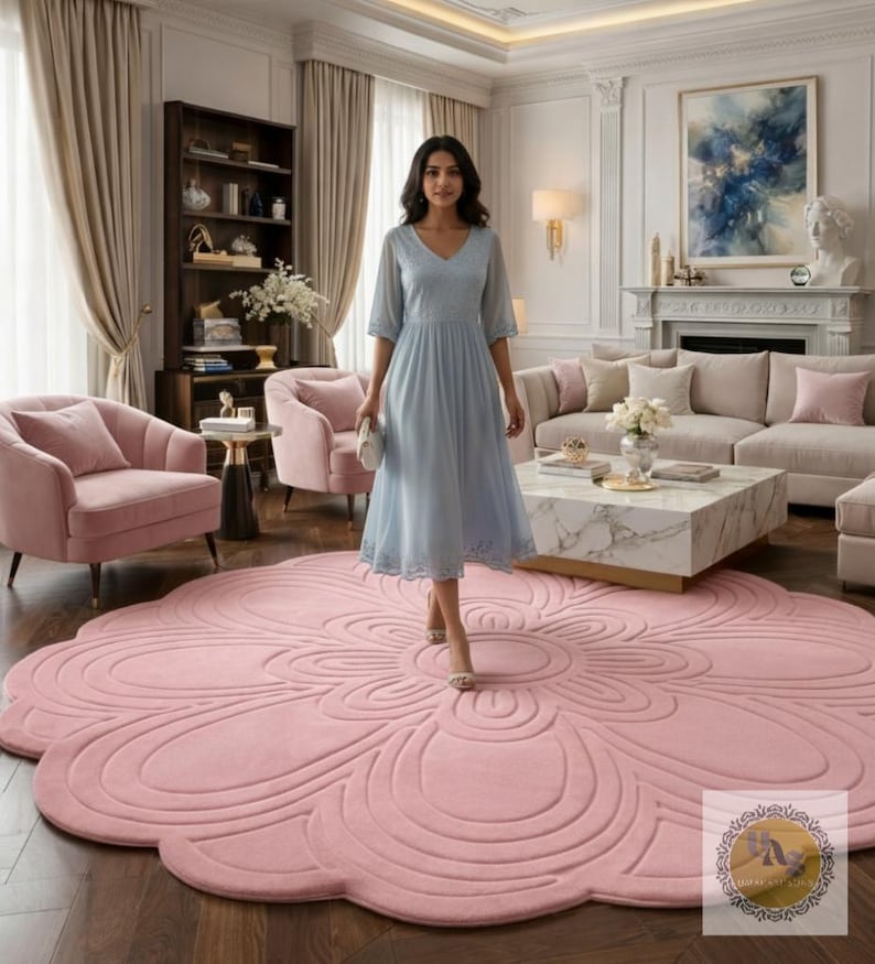 Puede incluir: Una alfombra rosa claro en forma de flor domina una sala de estar. El dise&ntilde;o de la alfombra presenta un patr&oacute;n circular central con bordes en forma de p&eacute;talo. La habitaci&oacute;n incluye un vestido azul claro, sillones rosas, un sof&aacute; y una mesa de centro de m&aacute;rmol.