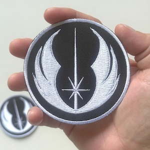 以下が含まれることがあります： 中央の垂直線、星、翼のような形が特徴的な、白と黒の丸いパッチ。背景には2つ目のパッチが見えます。