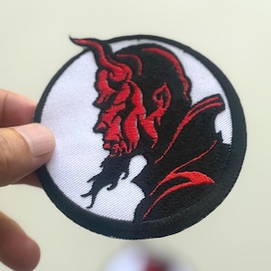 Può includere: Toppa ricamata raffigurante un profilo di diavolo rosso all'interno di un cerchio bianco, bordato di nero. Il diavolo ha corna e barba. Adatta per abbigliamento o accessori.