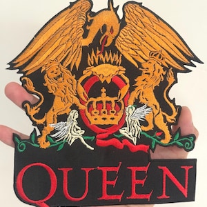 Op de afbeelding: Geborduurde patch met het Queen-wapen in goud, rood en zwart. Het ontwerp omvat een kroon, leeuwen, engelen en een feniks. Het woord "QUEEN" is rood geborduurd op een zwarte banner aan de onderkant.