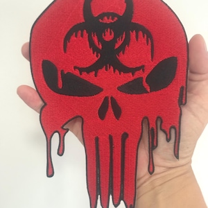 Może przedstawiać: Czerwona naszywka z czarnym wzorem czaszki z kroplami i symbolem zagrożenia biologicznego. Naszywka jest wykonana z tkaniny i ma szytą obwódkę.