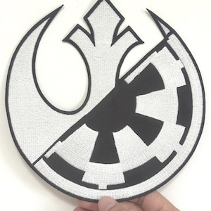 May include: Embroidered patch featuring a split design with a white rebel symbol on the left and a black Imperial cog on the right. The patch is circular with a black border and is held by a hand.