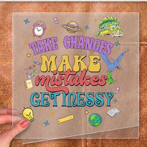 May include: A clear DTF transfer sheet featuring the text "TAKE CHANCES MAKE MISTAKES GET MESSY" in colorful, retro-style fonts. The design includes illustrations of a school bus, a pterodactyl, a planet, a lightbulb, a globe, and school supplies.