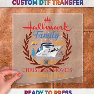 May include: A clear DTF transfer sheet featuring a graphic with a cruise ship, a crown, a laurel wreath, and the text Hallmark Family Cruise 2026 Christmas Movies Watching Shirt with the name Andre printed on the side of the ship in blue and red.