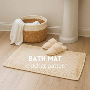 May include: A cream-colored rectangular bath mat with a textured border, paired with matching slippers. A woven basket with a white towel and a white pedestal sink are in the background. The text "BATH MAT crochet pattern" is displayed on the mat.