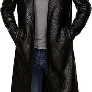 Puede incluir: Abrigo largo de cuero negro con un patrón texturizado. El abrigo tiene solapas con muescas, bolsillos y un diseño largo y fluido. La persona lleva una camisa gris y vaqueros azules.