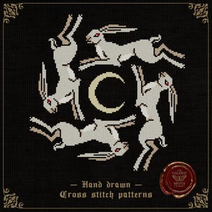 May include: Cross stitch pattern showing six white hares in a circular design around a crescent moon. The hares have red eyes against a black backdrop. Text reads "Hand drawn Cross stitch patterns".