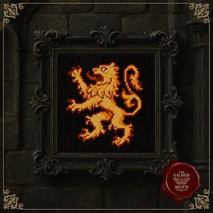 May include: A framed cross-stitch featuring a golden lion rampant on a black background. The lion is rendered in pixelated detail, with shades of gold and orange. The ornate black frame adds a touch of elegance. The Gilded Moth logo is in the bottom right corner.