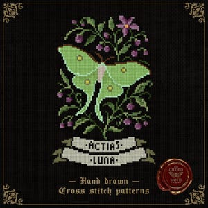 May include: Cross-stitch design of a green luna moth with the text "Actias Luna" on a banner, set against a black backdrop. The moth is framed by green foliage, purple berries, and flowers. The words "Hand drawn Cross stitch patterns" are below.
