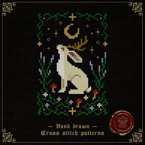 Könnte beinhalten: Kreuzstichmuster mit einem weißen Hasen mit Geweih, der zu einem Halbmond und Sternen aufblickt. Das Design umfasst grünes Laub, Pilze und den Text "Hand drawn Cross stitch patterns" auf schwarzem Hintergrund.