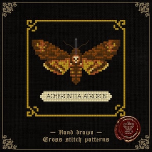 Op de afbeelding: Een kruissteekpatroon met een bruine en gele doodshoofdvlinder, met de naam "ACHERONTIA ATROPOS" eronder. Het ontwerp is goudkleurig omlijst op een zwarte achtergrond, met de tekst "Hand drawn Cross stitch patterns".