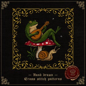 May include: Cross-stitch design of a green frog playing a lute on a red and white mushroom, with a snail and foliage below. The image is framed with a gold border on a black background. Text reads "Hand drawn Cross stitch patterns".