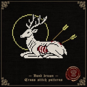 Könnte beinhalten: Kreuzstichmuster mit einem weißen Hirsch mit Geweih, durchbohrt von Pfeilen und einem roten Herzen. Der Hirsch ist vor einem schwarzen Hintergrund mit einem gelben Heiligenschein platziert. Der Text lautet "Hand drawn Cross stitch patterns".