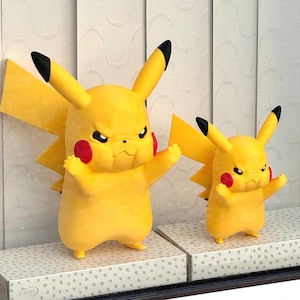 May include: Two yellow Pikachu figures with black-tipped ears and red cheeks, both displaying an angry facial expression with furrowed brows. The figures are standing on two separate rectangular boxes with a light green dotted pattern.
