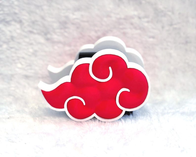 May include: A three-dimensional cloud-shaped object featuring a vibrant red center with rounded, swirling edges outlined in a thick white border. The design has a layered appearance with a black base visible behind the red cloud shape.