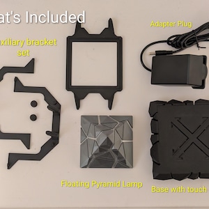 May include: A collection of black components for a floating pyramid lamp, including an auxiliary bracket set, a square frame, an adapter plug, a pyramid-shaped lamp, and a base with touch control. The text "What's Included" is at the top.