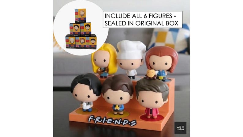 May include: A set of six Friends character figurines displayed on an orange stand with the show's logo. The figurines are in a cartoon style, each with unique outfits and hairstyles. The text "INCLUDE ALL 6 FIGURES - SEALED IN ORIGINAL BOX" is visible.