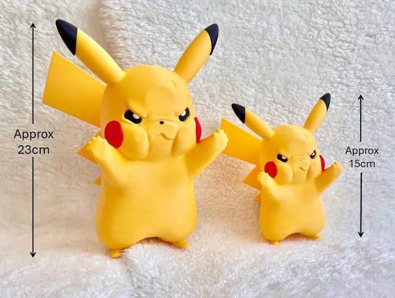 Puede incluir: Dos figuras amarillas de Pikachu con orejas de puntas negras y mejillas rojas, ambas con una expresi&oacute;n facial de enfado. La figura m&aacute;s grande mide aproximadamente 23 cm de altura y la m&aacute;s peque&ntilde;a mide aproximadamente 15 cm de altura.