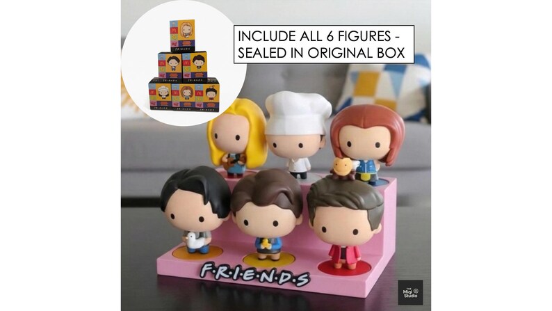 May include: A display of six Friends character figurines on a pink stand with the show's logo. The figurines have large heads and are in various outfits. The text reads: "INCLUDE ALL 6 FIGURES - SEALED IN ORIGINAL BOX."
