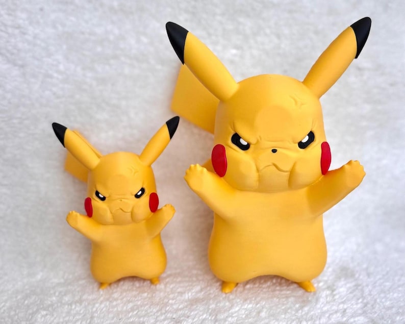 May include: Two yellow Pikachu figures with black-tipped ears and red circular cheeks. Both figures feature a stern, frowning facial expression with furrowed brows, standing with arms raised in a defensive posture, rendered in a smooth matte finish.