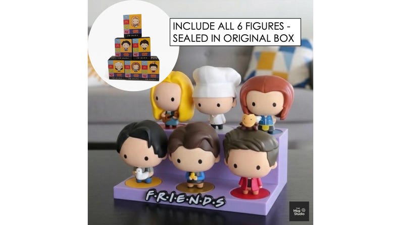 May include: A set of six Friends character figurines displayed on a purple stand with the show's logo. The figurines are in a cartoon style, with the text "INCLUDE ALL 6 FIGURES - SEALED IN ORIGINAL BOX" in the background.