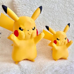 May include: Two yellow Pikachu figures with black-tipped ears and red cheeks, both displaying an angry facial expression. The larger figure measures approximately 9.06 inches in height, while the smaller figure measures approximately 5.91 inches.